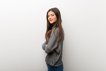 Teenager girl on isolated white backgorund keeping the arms crossed in lateral position while smiling