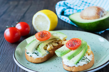 Fototapeta na wymiar Toasts with avocado pieces, cherry tomatoes, scrambled eggs and soft cream cheese.