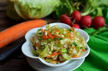 Young cabbage salad with carrot in a white bowl
