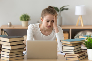 Tired girl sitting at work desk at home studying at laptop with books around, exhausted female fall asleep annoyed of learning, bothered student feel fatigue preparing for exam among course handbooks