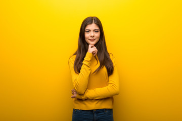 Teenager girl on vibrant yellow background smiling and looking to the front with confident face