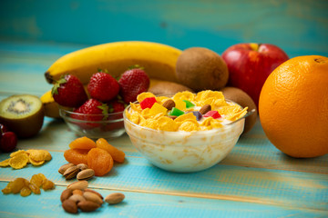 Tasty cornflakes with milk and fruits  in glass bowl