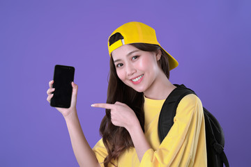 Chinese woman backpacker use smartphone to navigate the places for travel, yellow t-shirt clothing, purple background