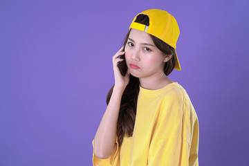 Chinese woman use smartphone to call her friend yellow t-shirt clothing, purple background
