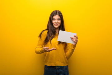 Teenager girl on vibrant yellow background holding an empty placard for insert a concept