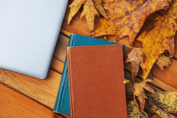 Beautiful maple leaves on vintage wooden background, border design. vintage color tone - concept of autumn leaves in fall season background and books,computer