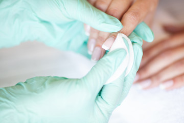 Fototapeta premium Woman Hand Care. Closeup Of Beautiful Female Hands Having Spa Manicure At Beauty Salon. Beautician Filing Clients Healthy Natural Nails With Nail File. Nail Treatment