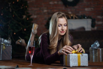 Beautiful woman in red dress lying on the floor and unpacking the gift