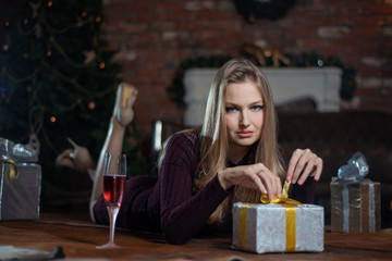 Beautiful woman in red dress lying on the floor and unpacking the gift