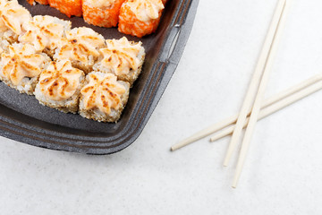 Sushi in plastic packaging. Baked sushi and chopsticks.