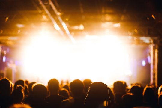 Crowd at the concert beside the stage in a bright warm stage lights
