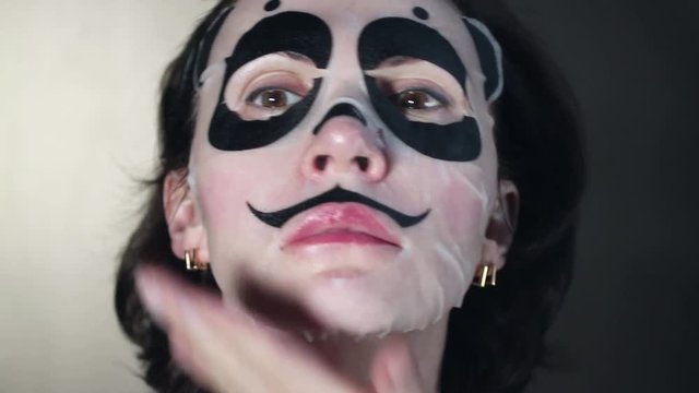 The girl makes a animal mask in the form of a panda face.