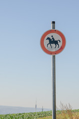 Das Verkehrszeichen ist ein rundes Schild mit rotem Rand und einem Reiter auf einem Pferd in der Mitte.