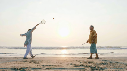 Active senior couple playing tai chi ballon ball at the beach. - obrazy, fototapety, plakaty