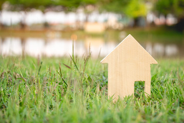 miniature wood house on green grass background with sunlight.Dream home with nature,mini icon.