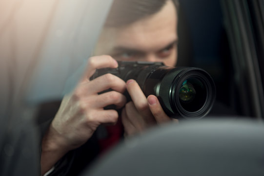 Close-up - Young Man Photorapher Sitting In The Car And Quickly Took A Photo On A Digital Camera. Concept Of Espionage And Photography