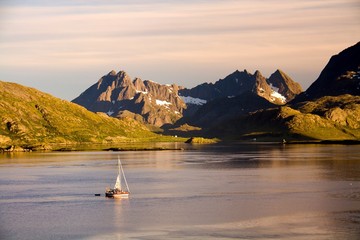 Yacht exploring lofoten fjord in evening sunlight, Norway