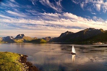 Yacht sailing near Fredvang in evening light, Lofoten islands, Norway