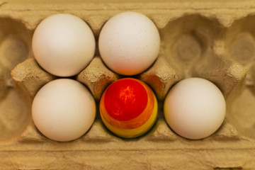 one colored egg in a package with ordinary white eggs. the concept of LGBT