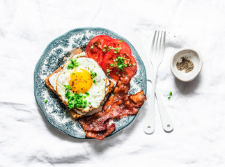 Nutritious breakfast - fried egg toast, bacon and tomatoes on a light background, top view