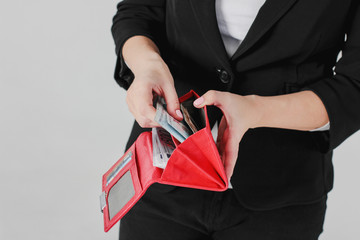 Women hands take money from red purse on gray background isolated close up