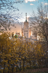 View of the Stalinist skyscraper through the trees at sunset, autumn view of the Stalinist skyscraper