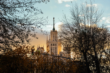 View of the Stalinist skyscraper through the trees at sunset