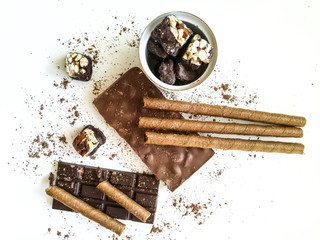 Different varieties of chocolate, chocolate tubes and cocoa on a white table