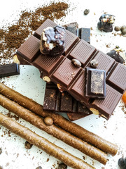 Different varieties of chocolate, chocolate tubes and cocoa on a white table