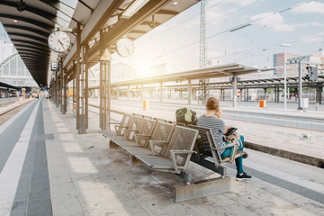 Frau wartet am leeren Bahnsteig am Bahnhof - obrazy, fototapety, plakaty