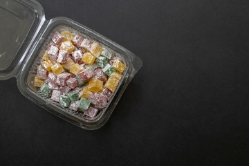 Turkish delights in a plastic container, isolated on black background. Copy space for text.