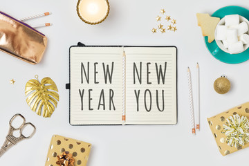 New Year resolutions concept with notepad and gift boxes on white background