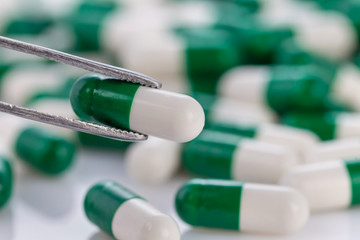 Close-up of green-white color medical pill on white background