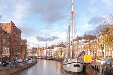 Scenic impression of the A river in the city of Groningen, showing the traditional houses along the canal, with a traditional ship in the foreground.