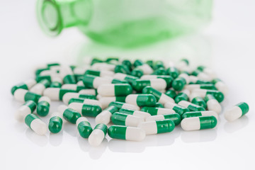 Close-up pile of green-white color medical pills on white background
