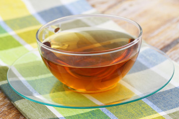 Black tea in transparent cup on checkered cloth, closeup
