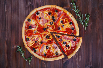 Pizza with cheese meat peppers and tomatoes on a wooden background