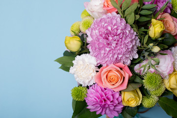 beautiful floral arrangement, pink and yellow rose, pink eustoma, green and pink chrysanthemum, white carnation, pink dahlia on a blue, turquoise background with space for text.