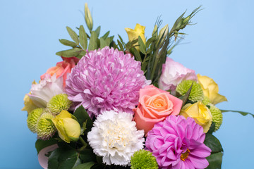 beautiful floral arrangement, pink and yellow rose, pink eustoma, green and pink chrysanthemum, white carnation, pink dahlia on a blue, turquoise background with space for text.