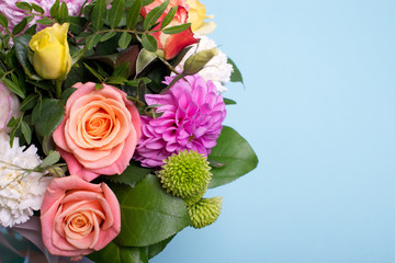 beautiful floral arrangement, pink and yellow rose, pink eustoma, green and pink chrysanthemum, white carnation, pink dahlia on a blue, turquoise background with space for text.
