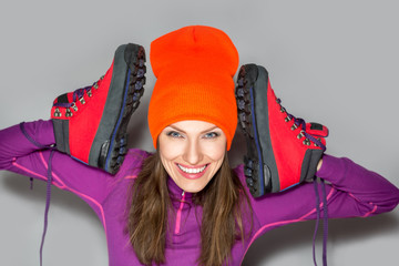 Funny young sport woman holding hiking boots