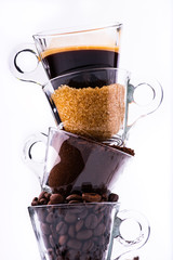 glass cups, in vertical sequence, with coffee beans, ground coffee, brown sugar and a creamy drink. still life