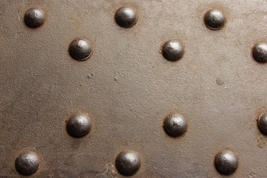 pattern of old metal rivets in flat face of steel sheet