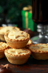 British Christmas mince pies with decoration, gifts, green tree branch on wooden rustic table