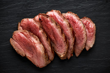 Medium rare venison steak on rustic dark stone board - obrazy, fototapety, plakaty