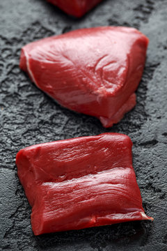 Raw Venison Steak On Black Rustic Table.