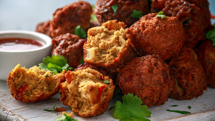 Indian Pakora snack spicy onion, red pepper with chilli sauce on white wooden board