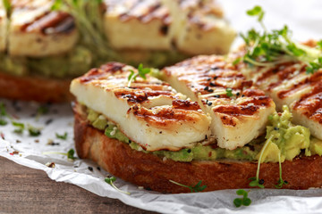 Avocado and grilled haloumi cheese toast with nigella and sesame seeds on crumpled paper. healthy breakfast