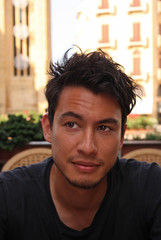 Portrait of a young man with wild dark hair and dark eyes sitting in a cafe