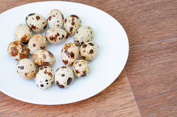 quail eggs on a white plate over wooden background